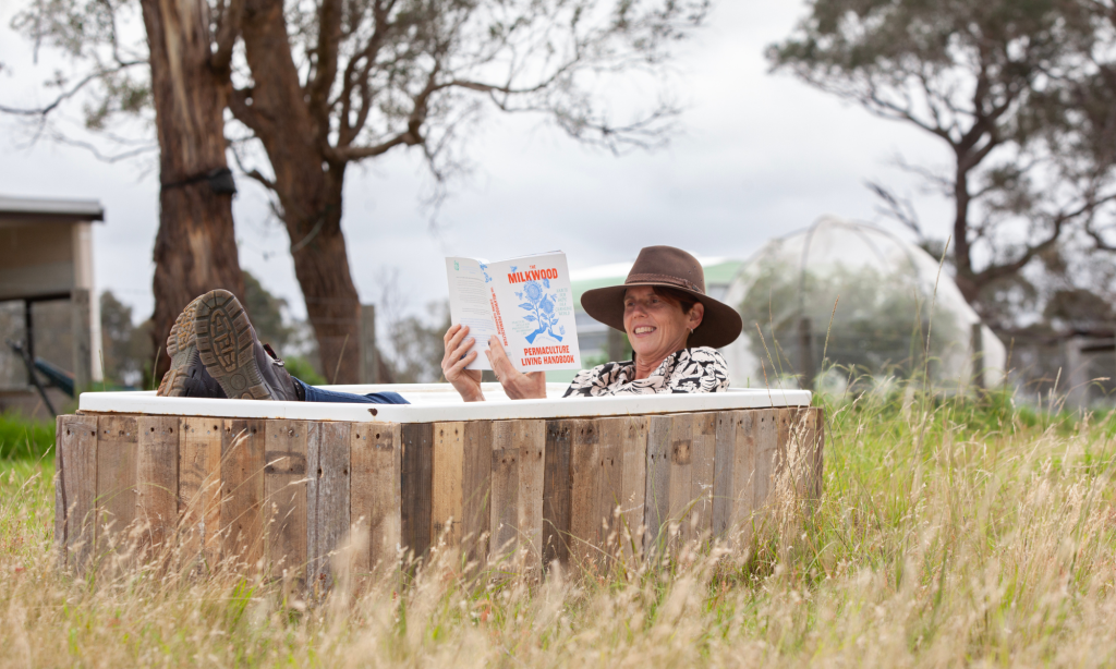 Photo of woman reading a book in outdoor bath at Yintarini Farm
